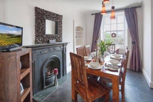 a dining room with a table and a fireplace at Goshen Cottage in Kelso