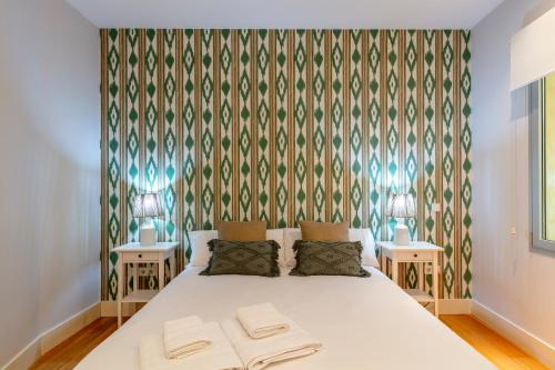 a bedroom with a white bed with two tables at Heima Retiro Park-Ibiza in Madrid