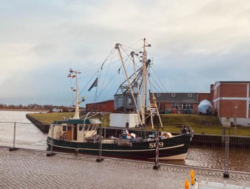 a small boat is docked in the water at Gasthaus Hafenblick in Tönning
