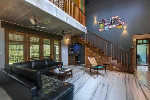 a living room with a black couch and a staircase at SaffronStays Ambaram, Pali in Māngaon