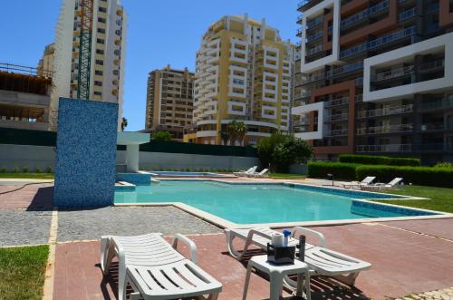 - une piscine avec 2 chaises longues et 2 bâtiments dans l'établissement ROCHA Tower 4D, à Portimão