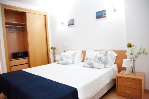 - une chambre dotée d'un lit blanc avec des oreillers bleus et blancs dans l'établissement ROCHA Tower 4D, à Portimão