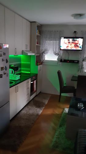 a kitchen with green and white cabinets and a television at Apartman Luna in Valjevo