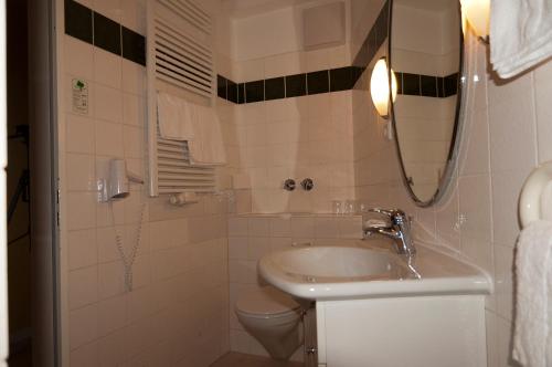 a bathroom with a sink and a toilet and a mirror at Hotel Haus Deutsch Krone in Bad Essen