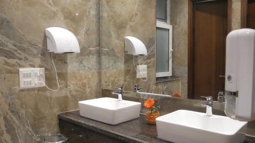 a bathroom with two white sinks and a mirror at Trinantara Resort & Spa in Kālāgarh