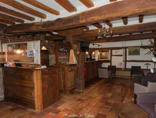 a restaurant with a bar in a room with wooden ceilings at Hostellerie des Tilleuls in Smuid