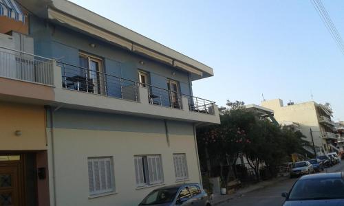 a building with a balcony with cars parked on the street at Sea to See in Néa Péramos