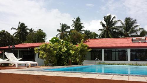 a villa with a swimming pool next to a house at Ranga Holiday Resort in Bentota