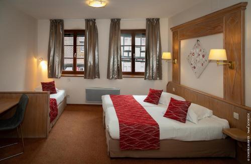 a hotel room with two beds and two windows at Hôtel De La Cloche in Obernai