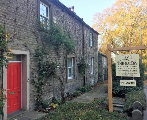 a red door and a sign in front of a brick building at The Bailey Shepherd's Hut and Holiday Cottage in Skipton
