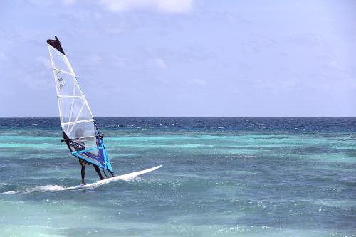 a person on a surfboard with a sail in the ocean at Kaani Village & Spa in Maafushi