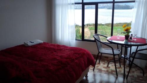 a bedroom with a bed and a table and a window at Cabañas Villas Del Lago in Cuítiva