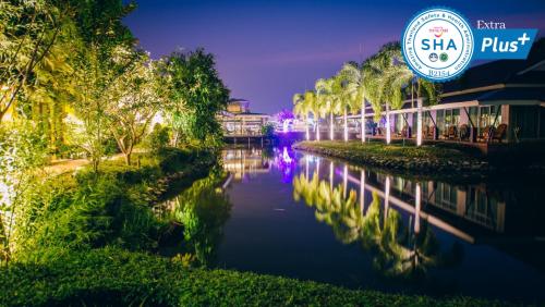 a river with palm trees and a sign that reads shahi plus at Good Times Resort Kanchanaburi in Kanchanaburi City