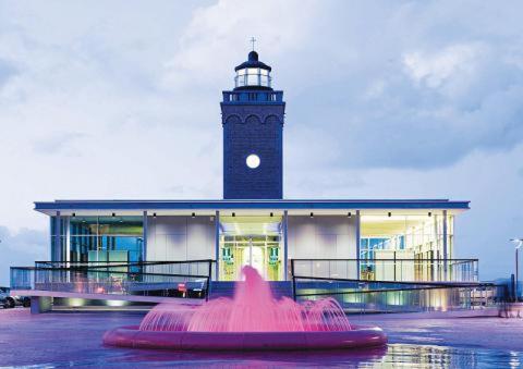 a lighthouse with a pink fountain in front of a building at Appartement Sunny home Deluxe in Knokke-Heist