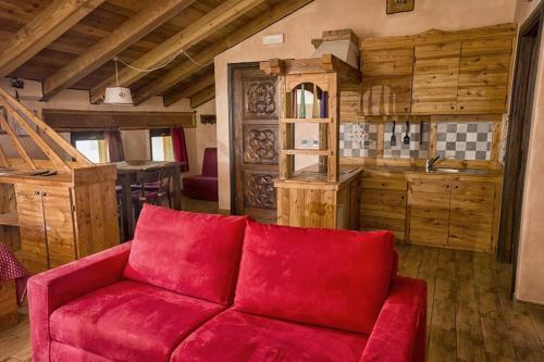 a red couch in a room with a kitchen at Agriturismo B&B Chèvres à Cheval in Aosta