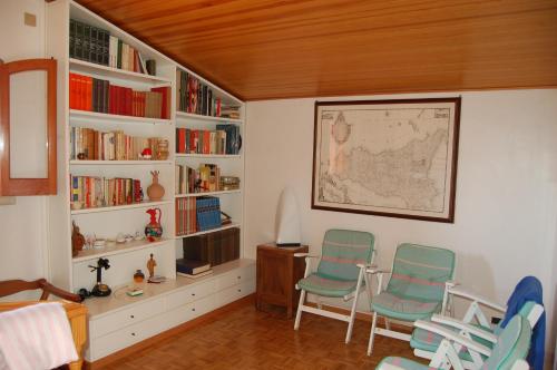 um quarto com duas cadeiras, uma secretária e estantes em Casa Romano - Marina di Modica em Marina di Modica