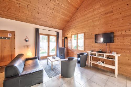 a living room with a leather couch and a television at Chalet de charme - Le Martinet in Ney