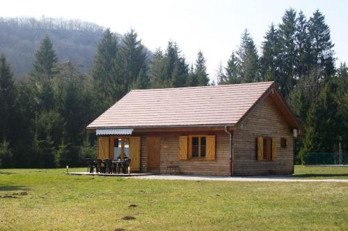 a small log cabin in a field with trees at Chalet de charme - Le Martinet in Ney