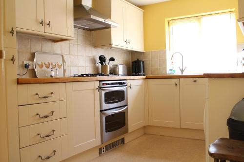 een keuken met witte kasten en een fornuis met oven bij Penrith Lodge in Stroud
