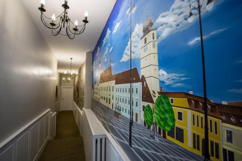 a hallway with a mural of a building and a clock tower at Casa Timpuri Vechi in Sibiu