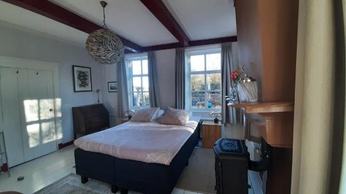 a bedroom with a bed in a room with windows at B&b Hoogholtje in Onderdendam