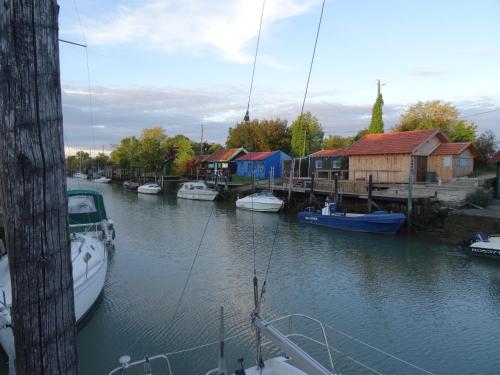 eine Gruppe von Booten, die in einem Fluss mit Häusern angedockt sind in der Unterkunft Gite 3 étoiles les Nougers in La Tremblade