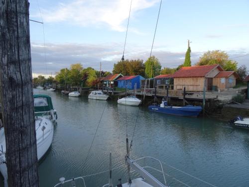 un groupe de bateaux amarrés dans une rivière avec des maisons dans l'établissement Gite 3 étoiles les Nougers, à La Tremblade