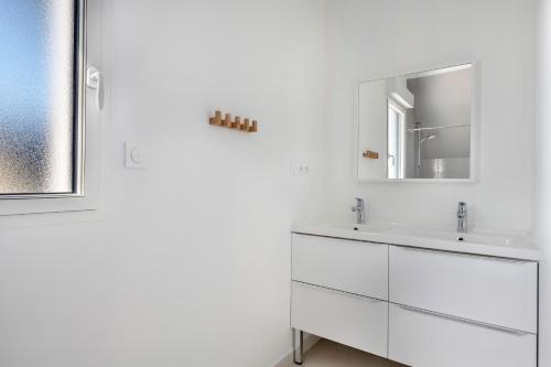 une salle de bain blanche avec deux lavabos et un miroir dans l'établissement Presqu'île de Rhuys, belle maison pour 10, à Sarzeau