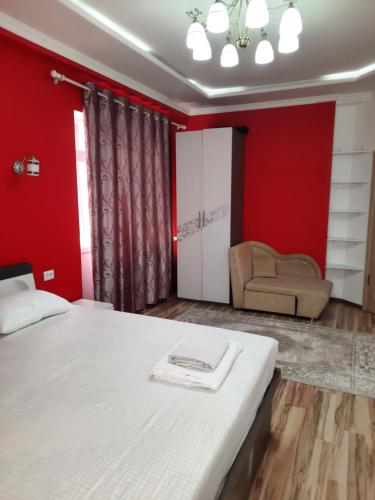 ein Schlafzimmer mit roten Wänden und einem Bett und einem Sofa in der Unterkunft Diplomat Apartments in Bischkek
