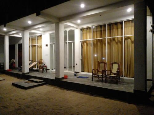 an empty room with chairs and windows at night at Sunray Beach House in Tangalle