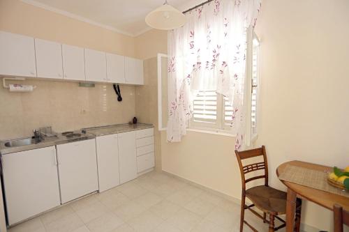 uma cozinha com armários brancos, uma mesa e uma janela em Studio Stari Grad em Herceg Novi