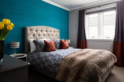 a bedroom with a bed with blue walls and a window at Bastle Retreats Farm Cottage in Duns