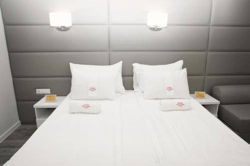 a large white bed with white pillows on it at Plovdiv City Center Hotel in Plovdiv