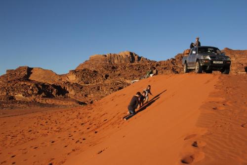 a group of people standing on a sand dune in the desert at Mohammed Mutlak Camp in Wadi Rum