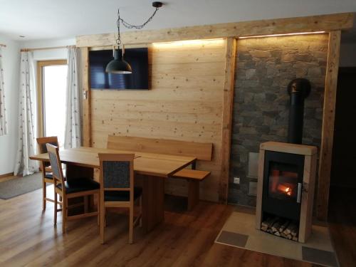 a dining room with a wooden table and a fireplace at Ferienwohnung Kaufbeurerhausblick in Hinterhornbach