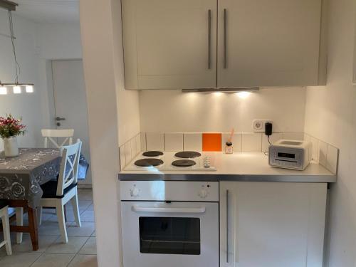 a kitchen with a stove top oven next to a table at Kleines Haus im Grünen in Hamburg