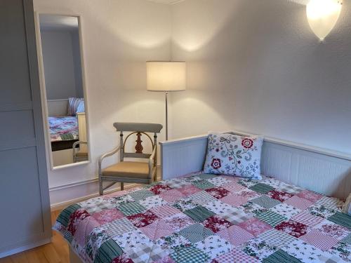 1 dormitorio con 1 cama con edredón y silla en Kleines Haus im Grünen, en Hamburgo
