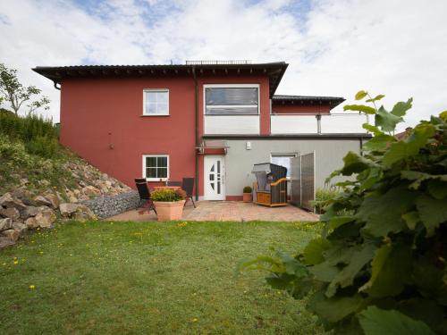 a red and white house with a yard at Benkelberg in Sitzerath