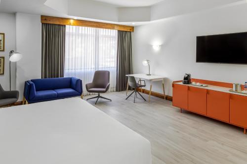 a hotel room with a bed and a tv and a desk at Radisson San Jose-Costa Rica in San José