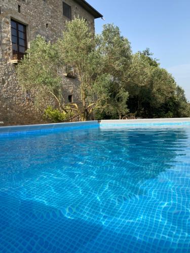 a large blue swimming pool next to a building at Mas Espuella in Argelaguer