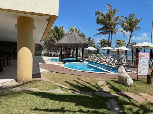 un resort con piscina attrezzata con sedie e ombrelloni di Elegance Hotel Natal Beira Mar a Natal