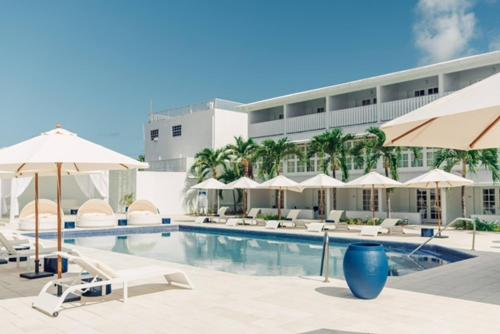 una piscina con sombrillas y sillas y un edificio en The SoCo House - All-Inclusive, en Castries