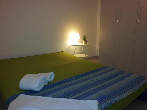 1 dormitorio con cama verde y mesa con lámpara en Casa Vacanza Comfort, en Ceglie Messapica