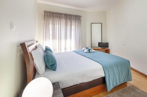 a bedroom with a large bed with a blue blanket at RH Charming Apartment - T3 in Barcelos