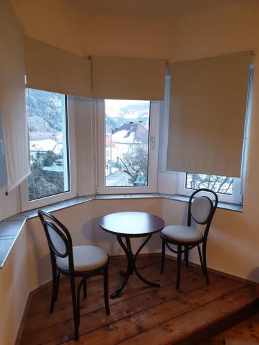 two chairs and a table in a room with two windows at Lerchenhof in Friesach