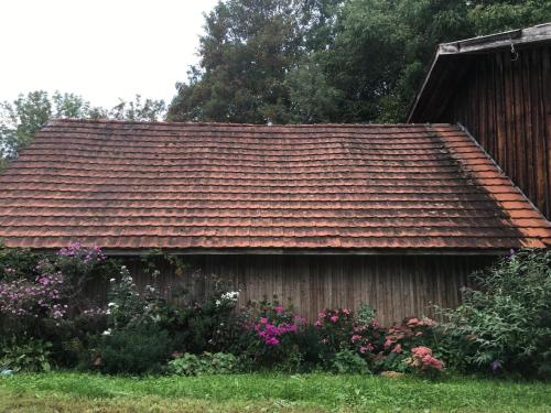 a house with a brown roof and some flowers at Ferienhof Weber Nieratz in Wangen im Allgäu