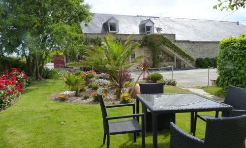 een patio met een tafel en stoelen in een tuin bij Lanévry, Ville d'Ys in Kerlaz