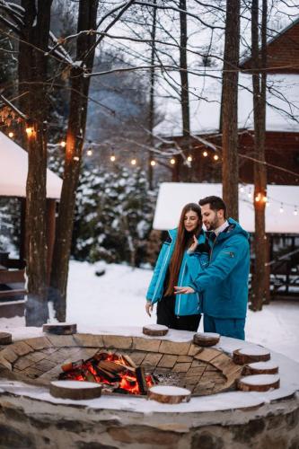 a man and woman standing next to a fire pit at Voevodyno Resort in Tur'ya Pasika