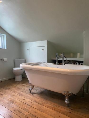 a bath tub in a bathroom with a toilet at Stunning 2 Bedroom Flat in a Central Location in New Alresford
