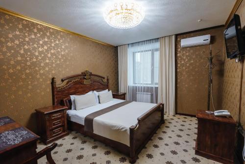 a bedroom with a bed and a television in it at Altyn Adam Hotel in Petropavlovsk